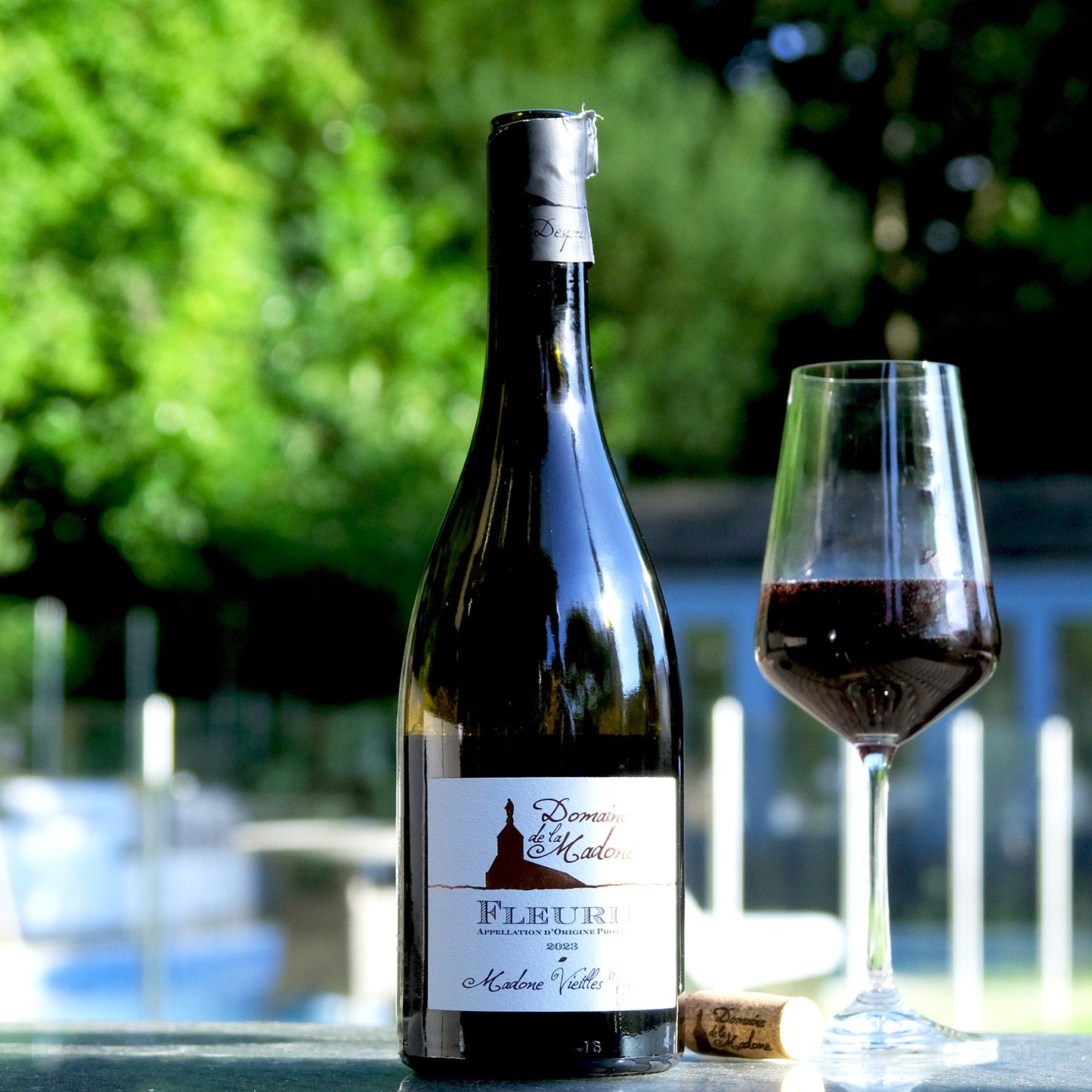 Domaine de la Madone Fleurie bottle and glass on table in sunshine