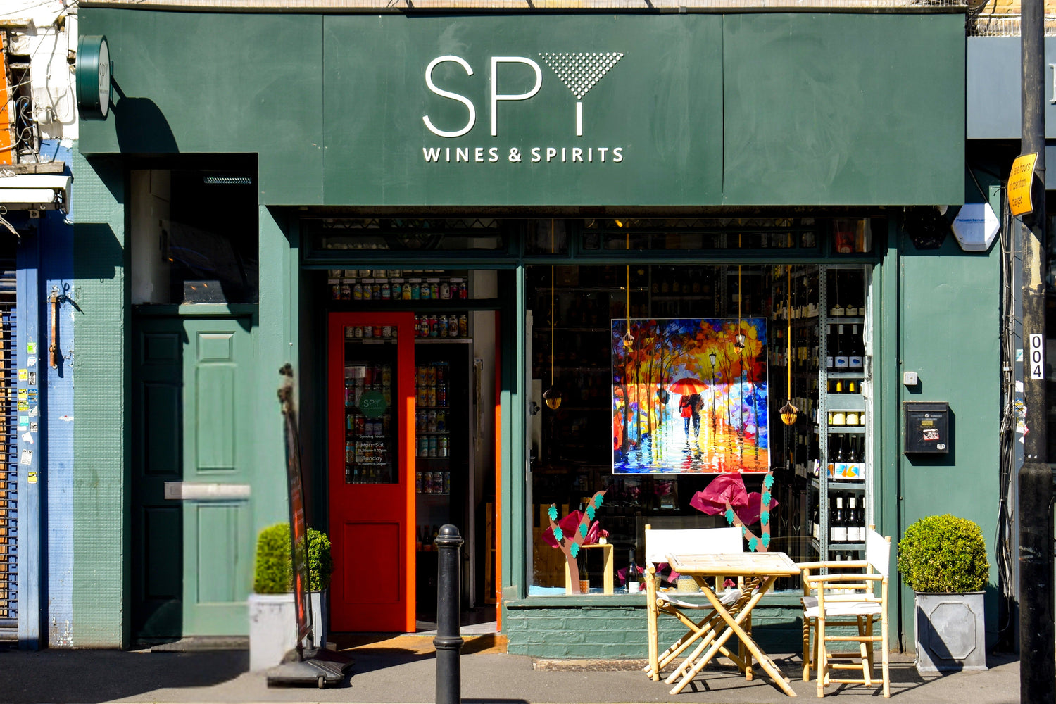 Green storefront with 'Spy Wines & Spirits' sign on a city street.
