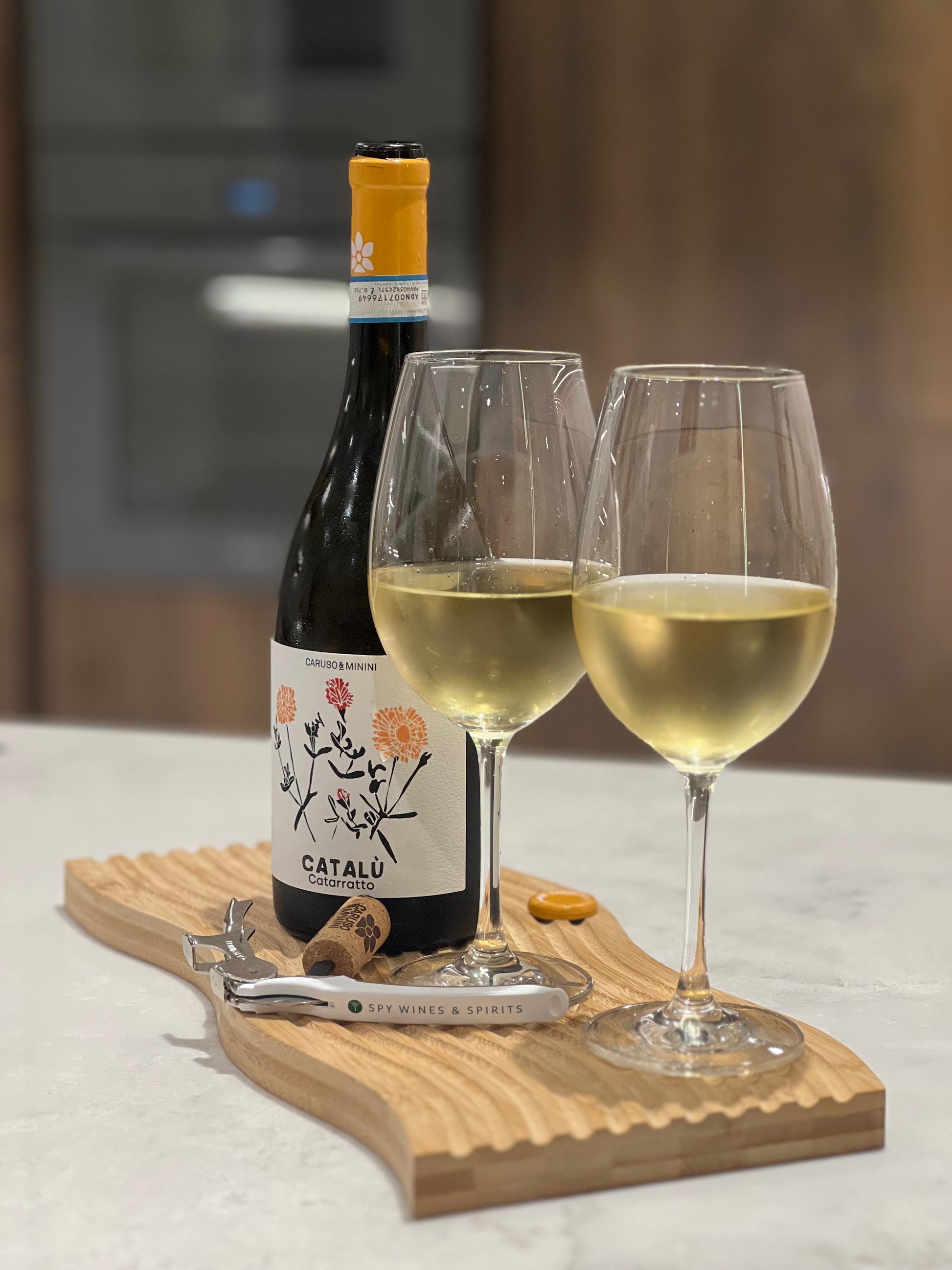 Catarratto Catalu Sicily Caruso & Minini in glasses with bottle and corkscrew on board on kitchen countertop