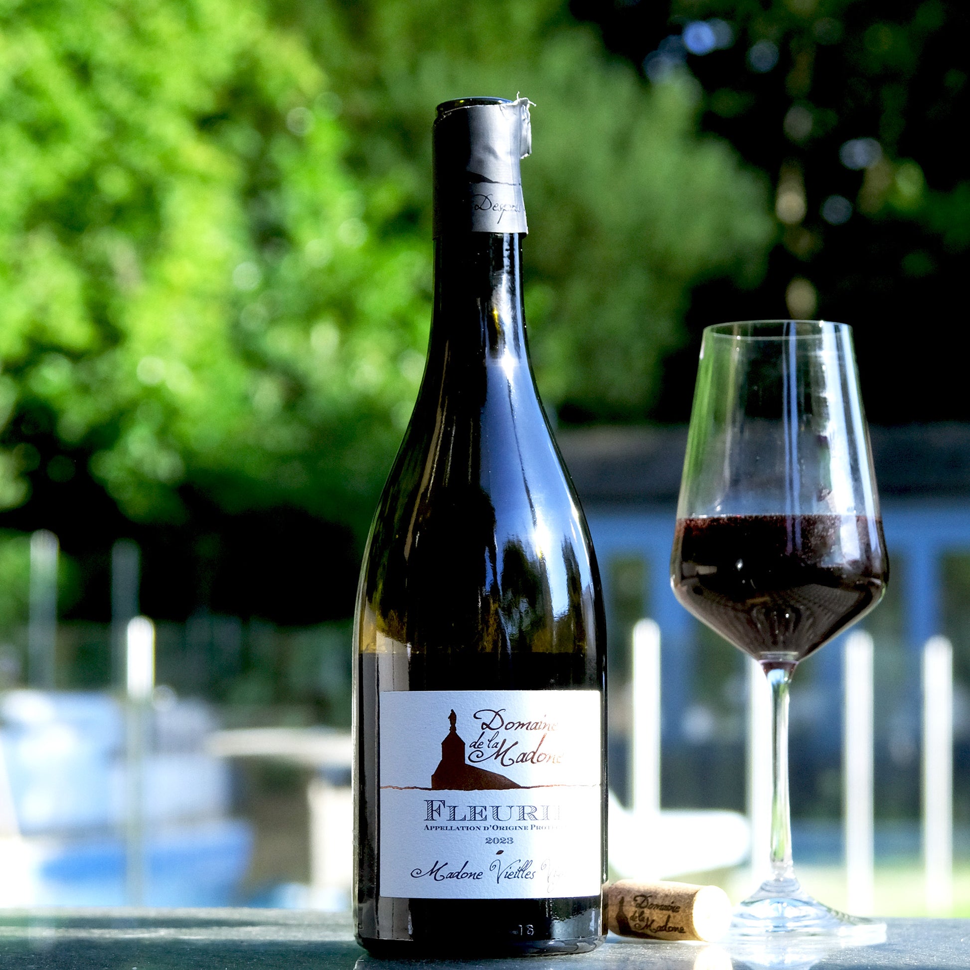 Domaine de la Madone Fleurie bottle and glass on table in sunshine