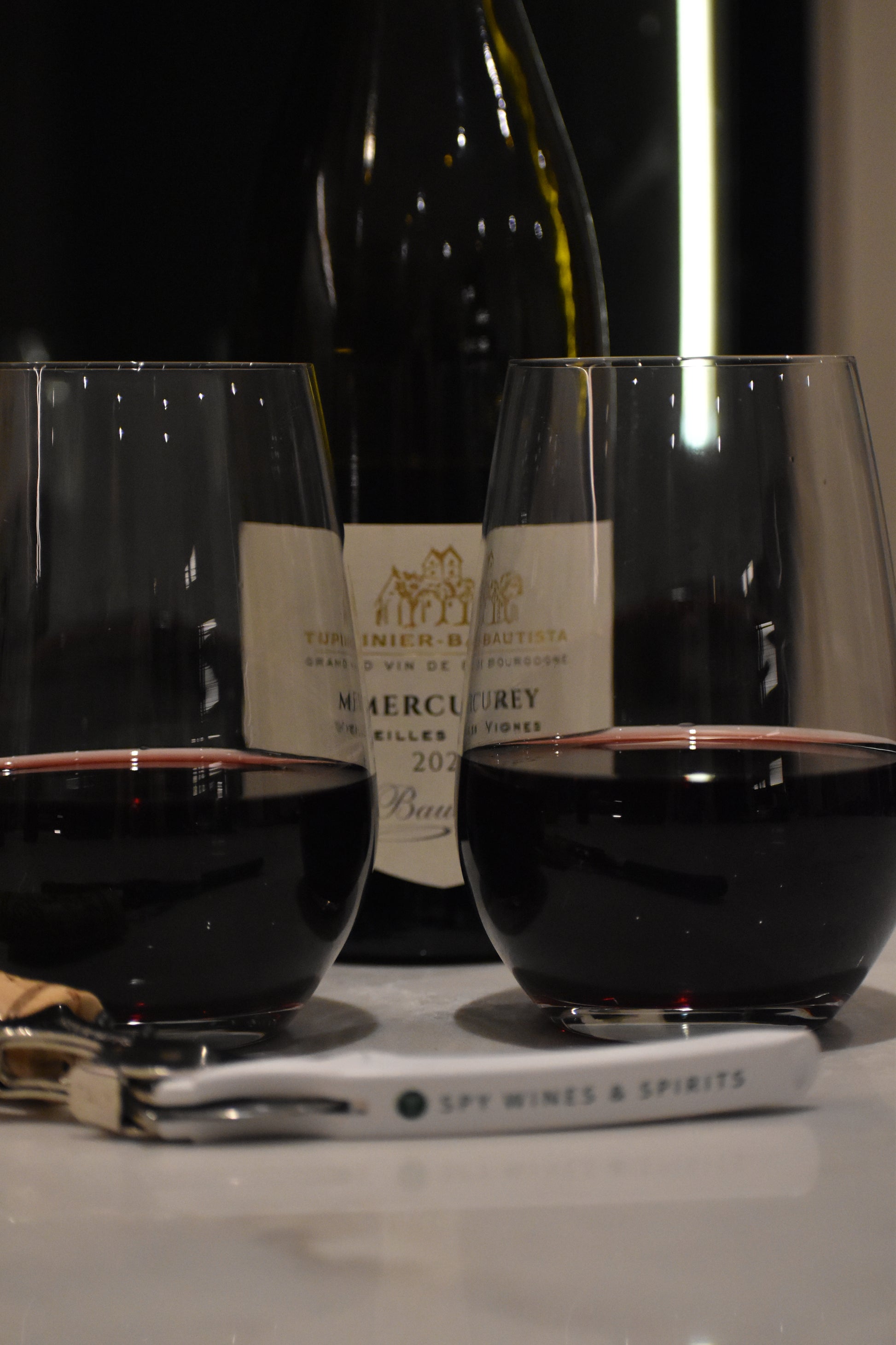 Pinot Noir in two glasses with bottle and corkscrew, kitchen in evening