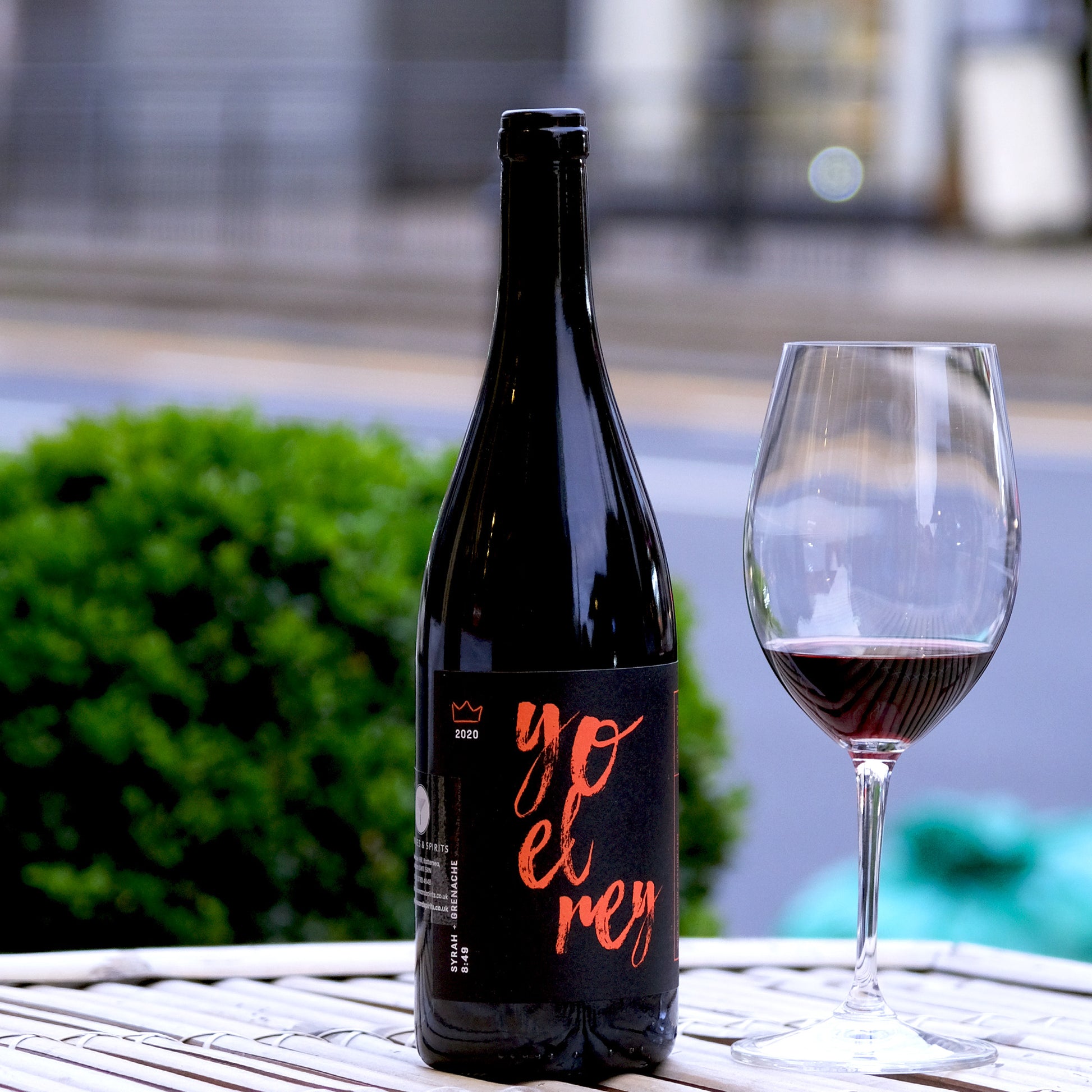 Yo El Rey 8:49 South Africa Syrah Blend Bottle with glass on table and plant