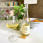 Max Sein Wein Blanc Wine Bottle Lifestyle Shot with a glass full of wine, flowers and a kitchen setting